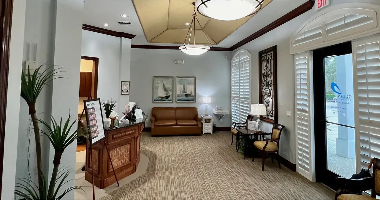 The lobby at Ocean Oaks Dental Group on 37th Place, Vero Beach: leather sofa, sailing prints and plantation shutters.