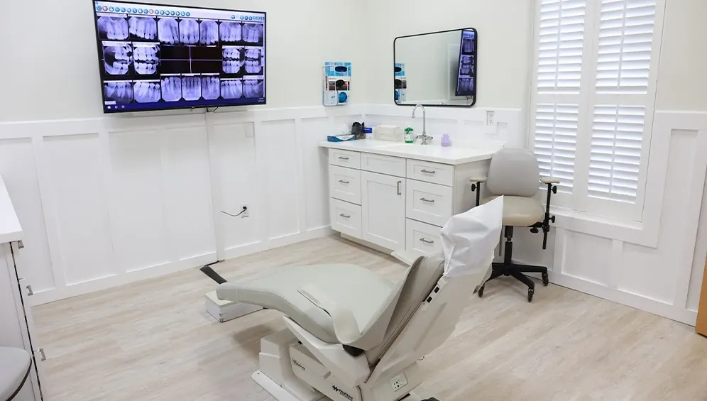 A bright Ocean Oaks treatment room with plantation shutters and x-rays on the wall screen.