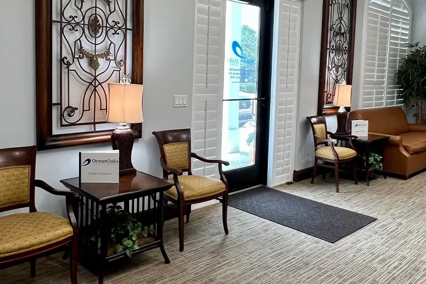 Cane-back chairs by a lamp in the Ocean Oaks lobby, beside the front door.